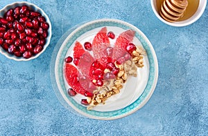 Yogurt with granola and red grapefruit, pomegranate for healthy breakfast. Bowl of greek yogurt with granola , honey and fresh
