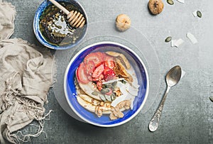 Yogurt, granola, seeds, berry and honey in blue ceramic bowl