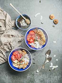 Yogurt, granola, seeds, fruits and honey in blue ceramic bowls