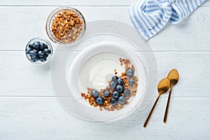 Yogurt. Greek Yogurt with granola and fresh blueberries in white bowl over old white wood background. Morning breakfast concept.