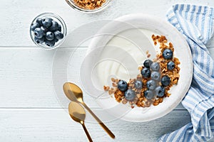 Yogurt. Greek Yogurt with granola and fresh blueberries in white bowl over old white wood background. Morning breakfast concept. H