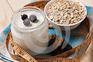 Yogurt in a jar, oat flakes and nuts, a measuring tape, the concept of a healthy diet