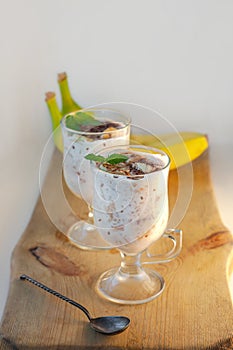 Yogurt Jelly Dessert with banana, strawberry, cocoa, fresh mint in a glass on wooden cut board.Healthy vegan sweet food