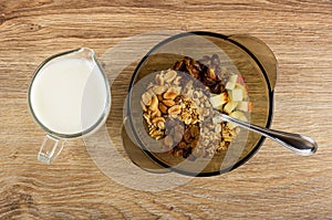Yogurt in jug, spoon in bowl with ingredients for muesli on wooden table. Top view