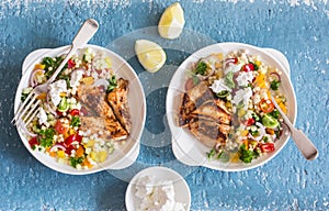 Yogurt marinated grilled chicken breast and israeli couscous and vegetables tabouli salad on a blue background