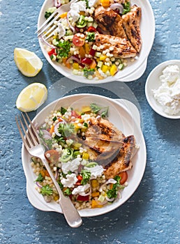 Yogurt marinated grilled chicken breast and israeli couscous and vegetables tabouli salad on a blue background