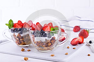 Yogurt with muesli and berries in small glass cups. Breakfast table