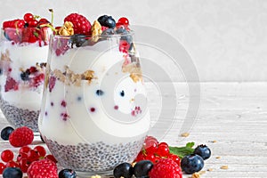 Yogurt with muesli, granola, berries and chia seeds in glasses