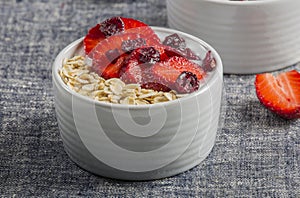 Yogurt with oat flake and fresh berries for healthy morning meal put on white wood background,