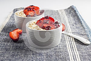 Yogurt with oat flake and fresh berries for healthy morning meal put on white wood background,