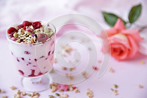 Yogurt parfait with fresh raspberry berries and rose on a light pink background. Healthy food. With copy space for text