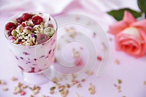 Yogurt parfait with fresh raspberry berries and rose on a light pink background. Healthy food. With copy space for text