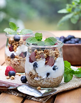Yogurt parfait with granola, blueberries and raspberries garnished with mint
