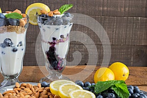 Yogurt parfait in a tall sundae glass with greek yogurt, fresh blueberries, almonds, lemon, and sprigs of mint