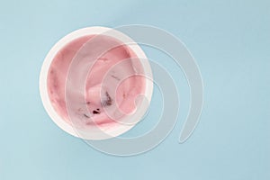 Yogurt in plastic cup close up - top view photo of strawberry yoghurt on pale blue background photo