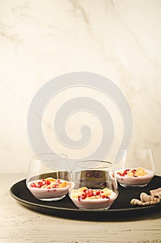 Yogurt with pomegranate and flakes on a black tray/homemade yogurt with pomegranate and flakes in glass on a black tray and white