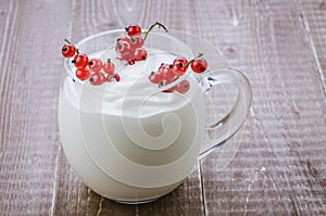 Yogurt with red currant in glass/yogurt with red currant in glass on a wooden background. Toned