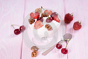 Yogurt with strawberries and cherries and walnuts in a glass bowl.