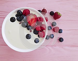 Yogurt, strawberry, raspberry, natural dieting refreshment blueberries homemade a pink wooden background,