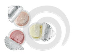 Yogurts of three different flavors - banana, cherry and strawberry, in open plastic cups isolated on a white background