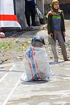 Children wearing a helmet having a sack race