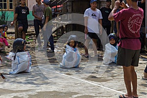 Children wearing a helmet having a sack race