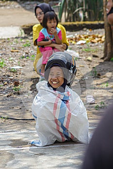 Children wearing a helmet having a sack race