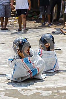Children wearing a helmet having a sack race