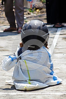 Children wearing a helmet having a sack race