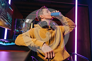 Yong caucasian pro gamer drinking energy drink while playing computer video games