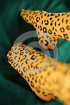 Yong female legs in tights with leopard print on emerald fabric
