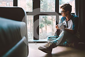 Yong guy plays on guitar sitting on the floor in living room