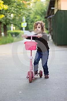 Yong kid girl ride on street with child scooter