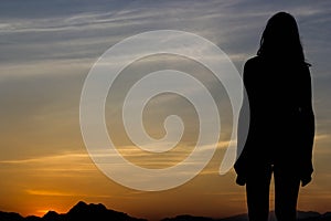 Yong woman standing on sunset backdrop