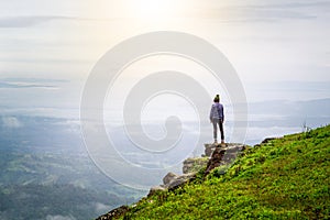 Yong woman standing on the top of the mountain observing