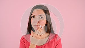 Yong woman washing her face with foam on pink background. Problem skin care concept. Morning routine