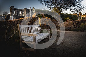 YORK, ENGLAND, DECEMBER 12, 2018: Wooden bench in an old park full of dry leaves. Concept of tranquility and peaceful moment