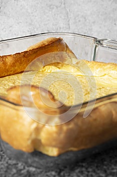 Yorkshire pudding in a glass dish on a black granite background.