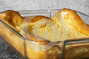 Yorkshire pudding in a glass dish on a black granite background.