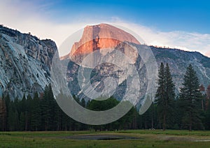 Yosemite National Park view of Half Dome from the Valley during colorful sunset with trees and rocks. California, USA