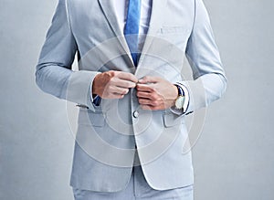 You achieve what you dress for. Studio shot of a businessman in a grey suit posing against a grey background.