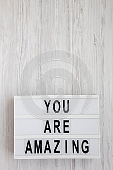 `You are amazing` words on a modern board on a white wooden background, overhead view. Top view, from above. Flat lay. Copy spac