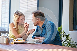 Are you buttering me up. Shot of a happy young woman giving her husband a taste of her food.