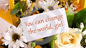 You can change the world, girl text written on a business card on a background of flowers