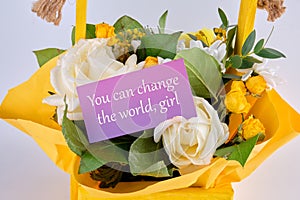 You can change the world, girl text written on a business card in a basket with blooming flowers