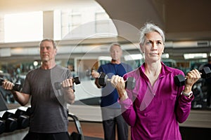 You can get old or you can get fit. a senior group of woman and men working out with weights together at the gym.
