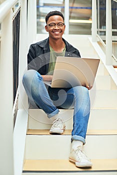 You can lose the paper and still stay productive. a young businessman using a laptop on the stairs of a modern office.