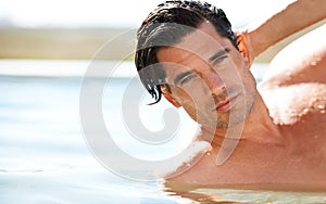 You can see the confidence in his chiseled face. Portrait of a sexy young man in a swimming pool running his hand