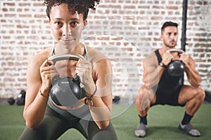 You can talk the talk but can you lift. two sporty young people using kettlebells while working out at the gym.