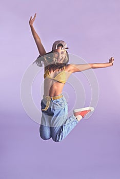You cant have hip without a hop. Studio shot of a beautiful young woman jumping for joy against a purple background.